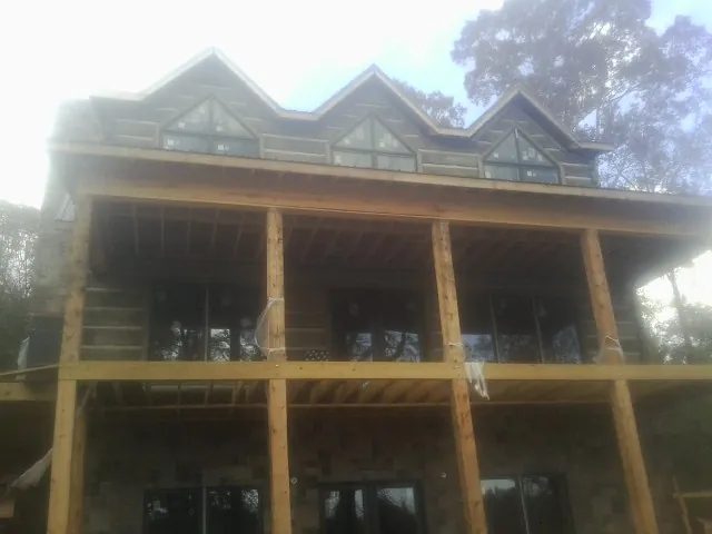 Dormers and porch framing on a large log home under construction — Roof Coating work by our crew in Pleasant Grove