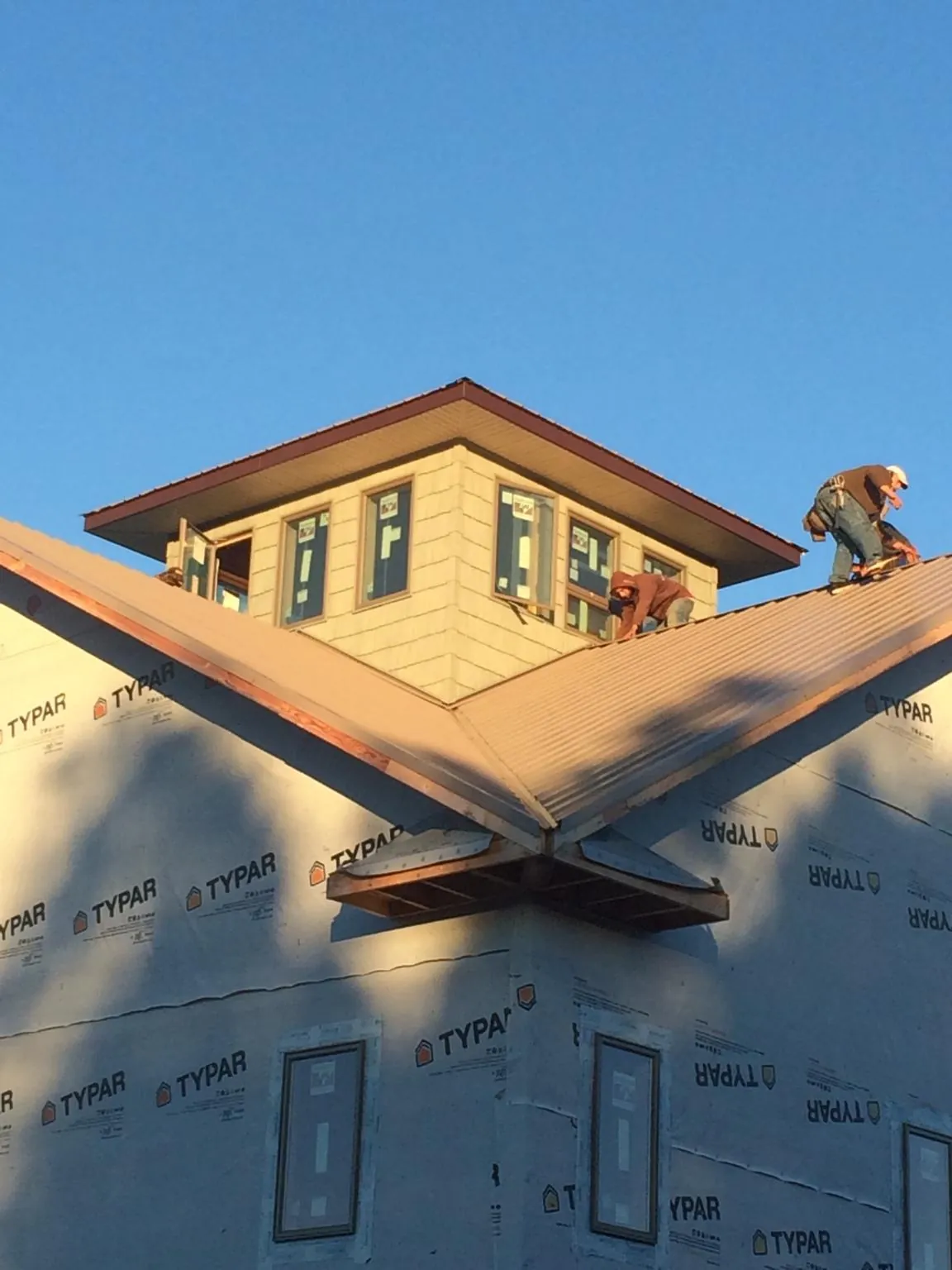 Roofers working around a rooftop cupola on a new metal roof at sunset — Roof Waterproofing in Pleasant Grove by Roofing Brothers